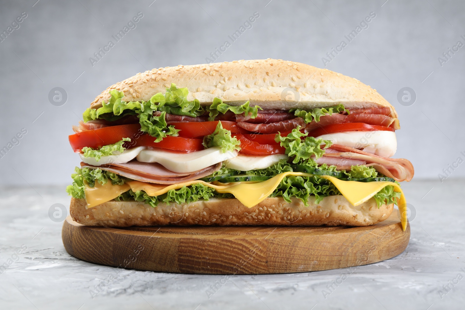 Tasty baguette sandwich with ham, cheese and vegetables on grey textured table, closeup Photo of Tasty baguette sandwich with ham, cheese and vegetables on grey textured table, closeup