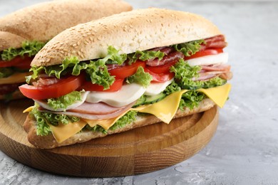 Photo of Tasty baguette sandwiches with ham, cheese and vegetables on grey textured table, closeup