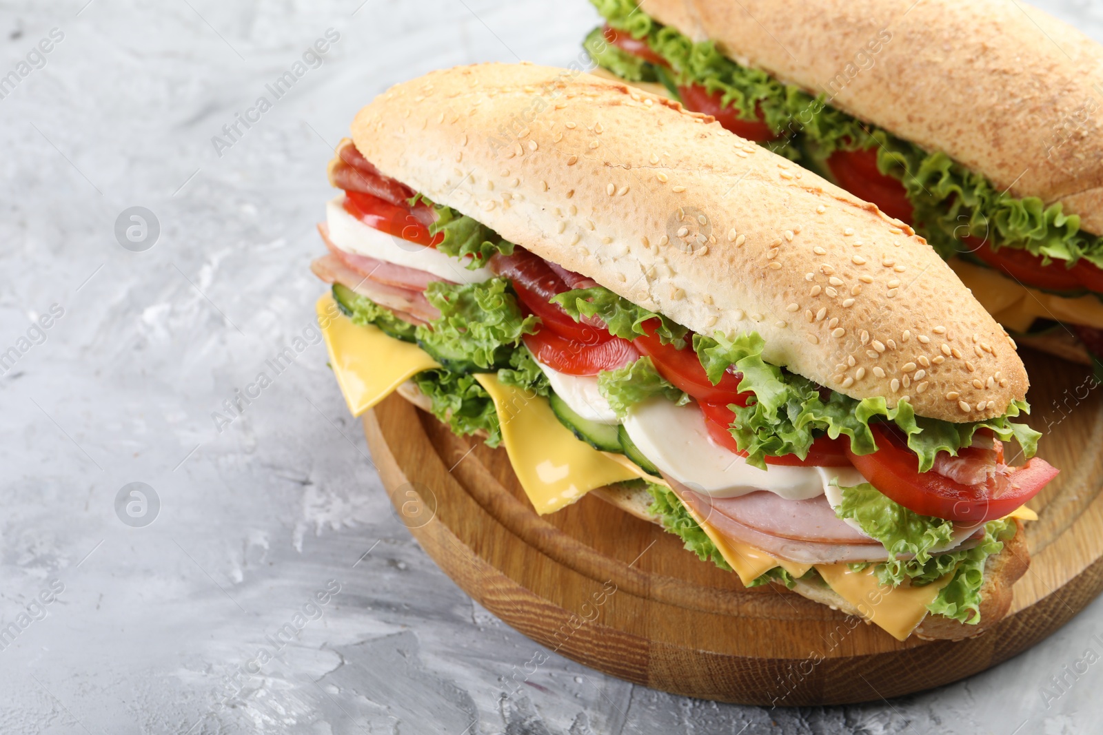 Tasty baguette sandwiches with ham, cheese and vegetables on grey textured table, closeup Photo of Tasty baguette sandwiches with ham, cheese and vegetables on grey textured table, closeup