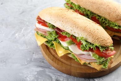 Photo of Tasty baguette sandwiches with ham, cheese and vegetables on grey textured table, closeup
