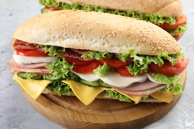 Photo of Tasty baguette sandwiches with ham, cheese and vegetables on grey textured table, closeup