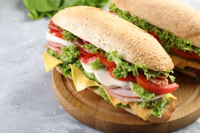 Photo of Tasty baguette sandwiches with ham, cheese and vegetables on grey textured table, closeup