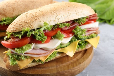 Photo of Tasty baguette sandwiches with ham, cheese and vegetables on grey table, closeup