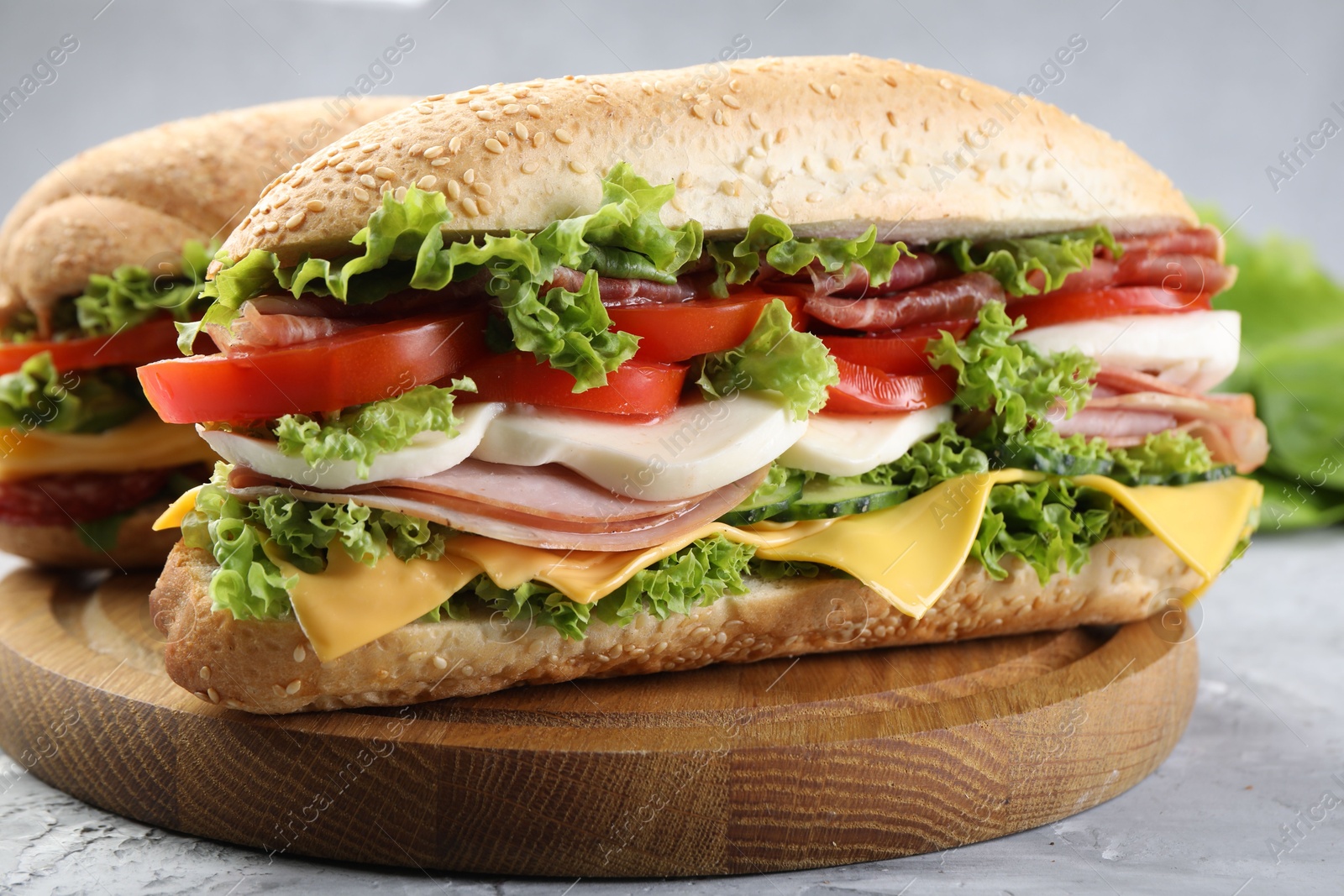 Tasty baguette sandwiches with ham, cheese and vegetables on grey textured table, closeup Photo of Tasty baguette sandwiches with ham, cheese and vegetables on grey textured table, closeup
