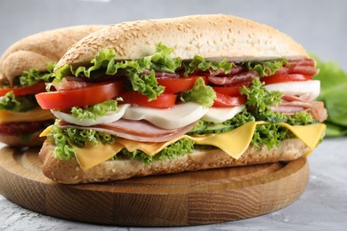 Photo of Tasty baguette sandwiches with ham, cheese and vegetables on grey textured table, closeup