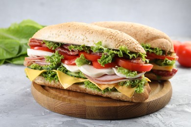 Photo of Tasty baguette sandwiches with ham, cheese and vegetables on grey textured table, closeup