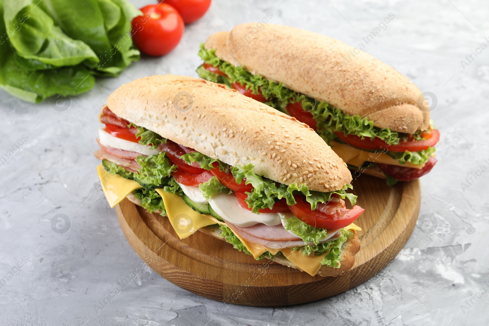 Tasty baguette sandwiches with ham, cheese and vegetables on grey textured table, closeup Photo of Tasty baguette sandwiches with ham, cheese and vegetables on grey textured table, closeup