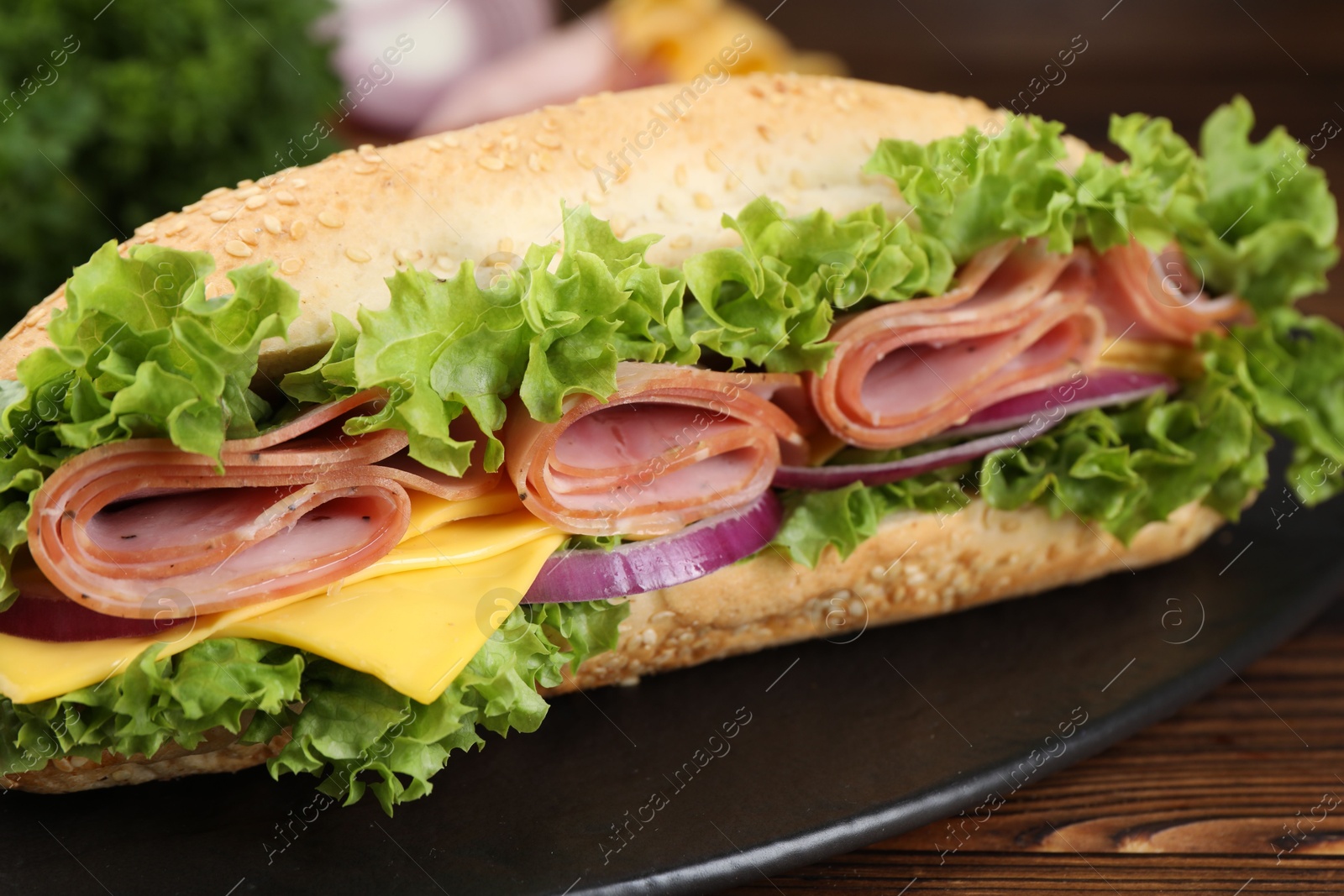 Tasty baguette sandwich with ham, cheese and vegetables on wooden table, closeup Photo of Tasty baguette sandwich with ham, cheese and vegetables on wooden table, closeup