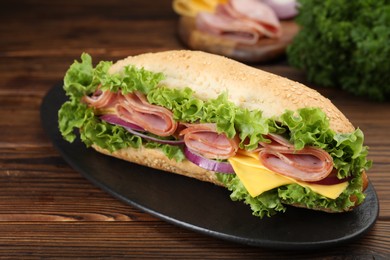 Photo of Tasty baguette sandwich with ham, cheese and vegetables on wooden table, closeup