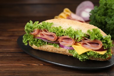 Photo of Tasty baguette sandwich with ham, cheese and vegetables on wooden table, closeup