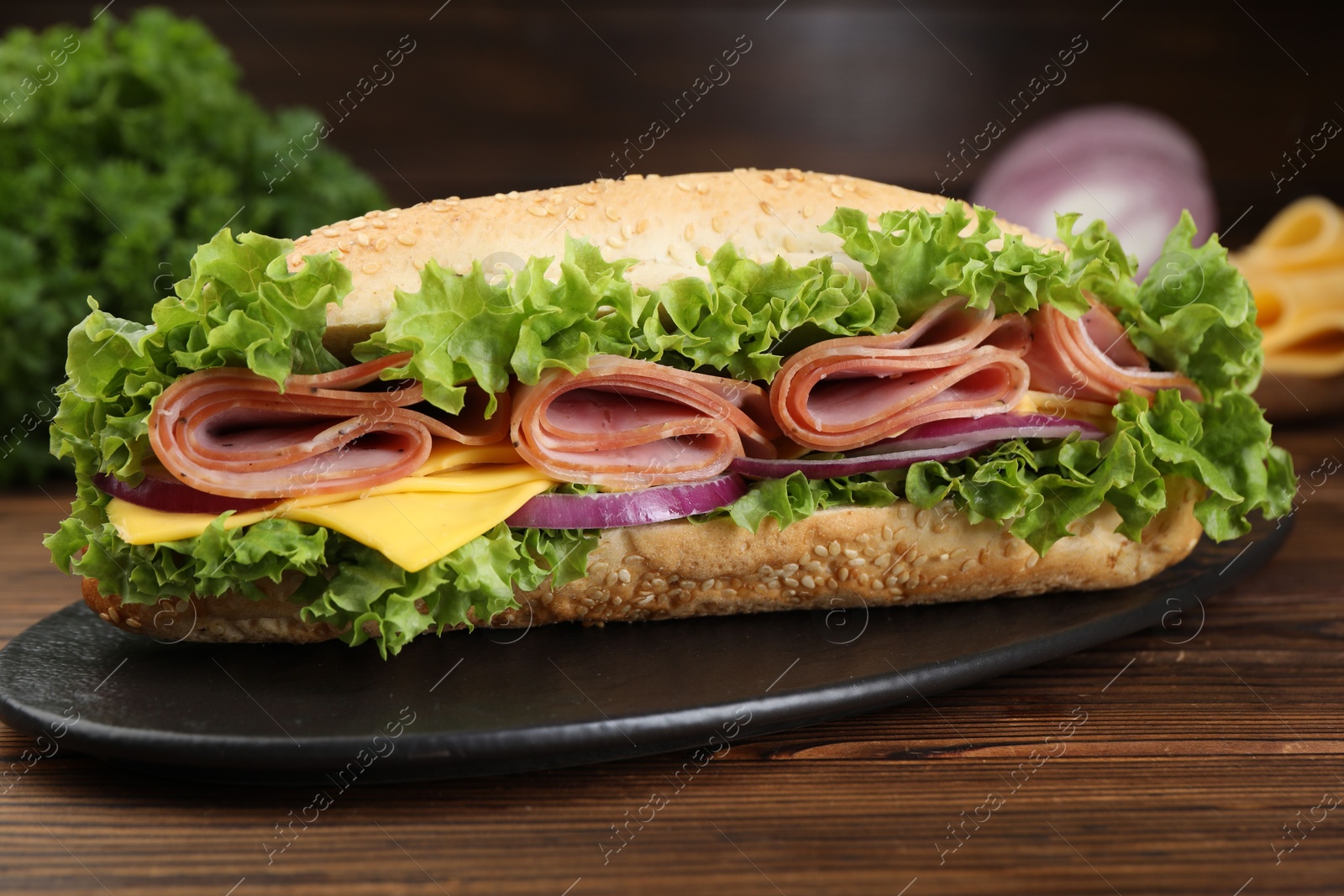 Tasty baguette sandwich with ham, cheese and vegetables on wooden table against dark background, closeup Photo of Tasty baguette sandwich with ham, cheese and vegetables on wooden table against dark background, closeup