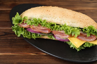 Photo of Tasty baguette sandwich with ham, cheese and vegetables on wooden table, closeup