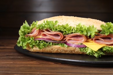 Photo of Tasty baguette sandwich with ham, cheese and vegetables on wooden table against brown background, closeup