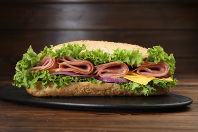 Photo of Tasty baguette sandwich with ham, cheese and vegetables on wooden table against brown background, closeup