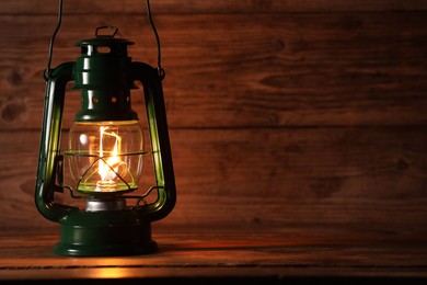 Photo of One vintage kerosene lantern on wooden table, space for text
