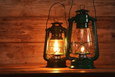 Photo of Vintage kerosene lanterns on wooden table, space for text