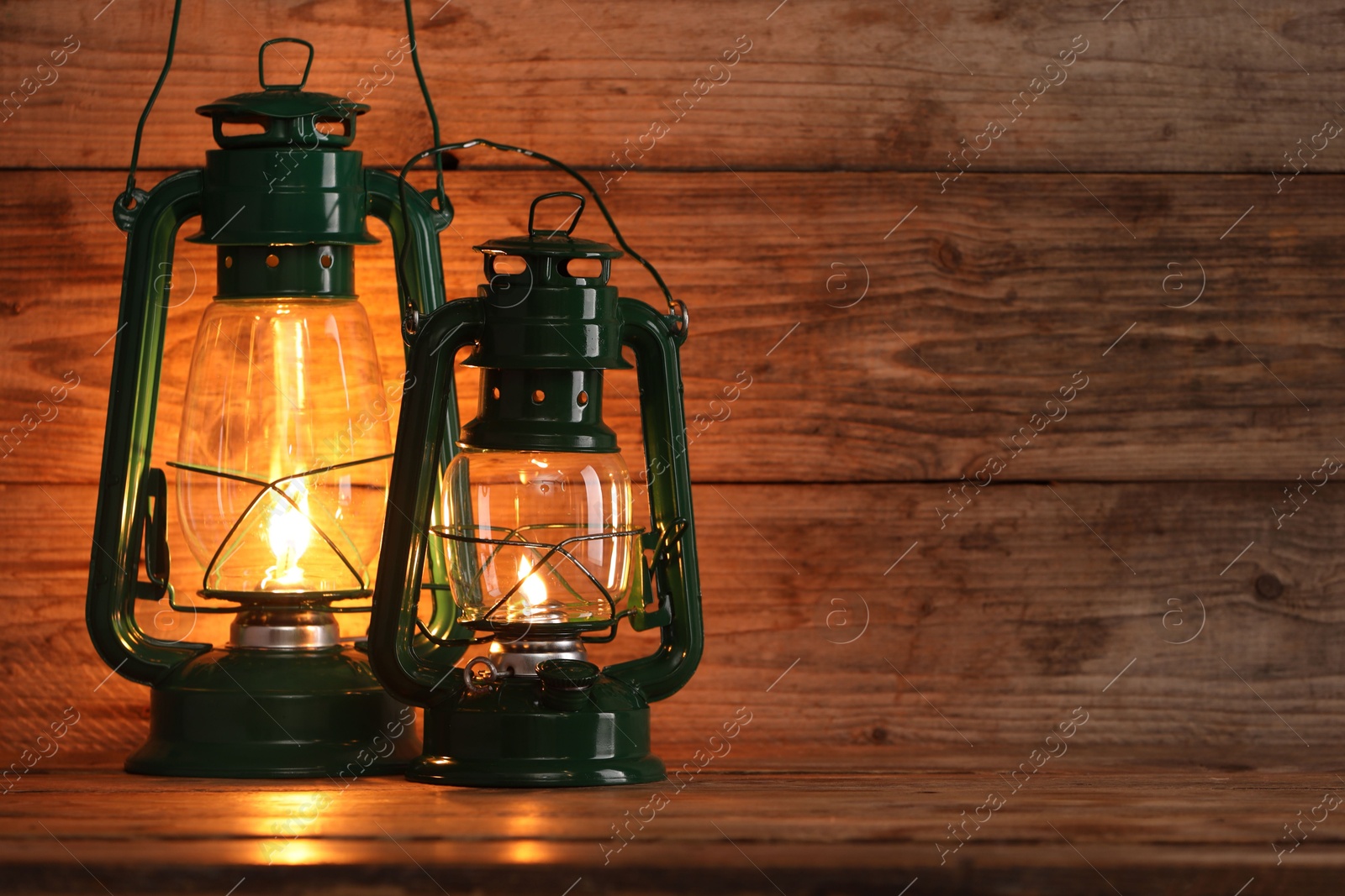 Photo of Vintage kerosene lanterns on wooden table, space for text