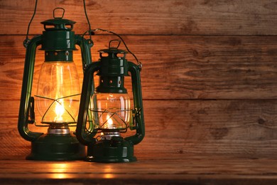 Photo of Vintage kerosene lanterns on wooden table, space for text