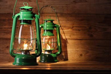 Photo of Vintage kerosene lanterns on wooden table, space for text