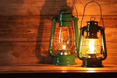Photo of Vintage kerosene lanterns on wooden table, space for text
