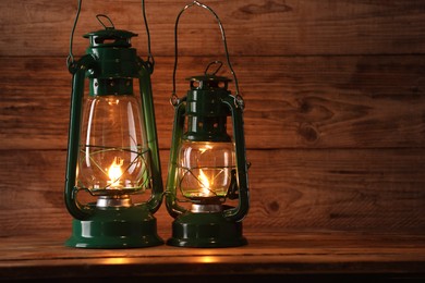 Photo of Vintage kerosene lanterns on wooden table, space for text