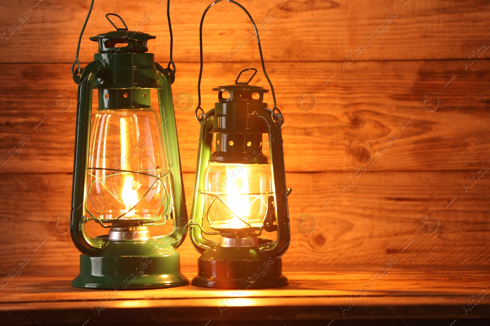 Photo of Vintage kerosene lanterns on wooden table, space for text