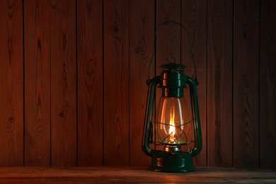 Photo of One vintage kerosene lantern on wooden table, space for text