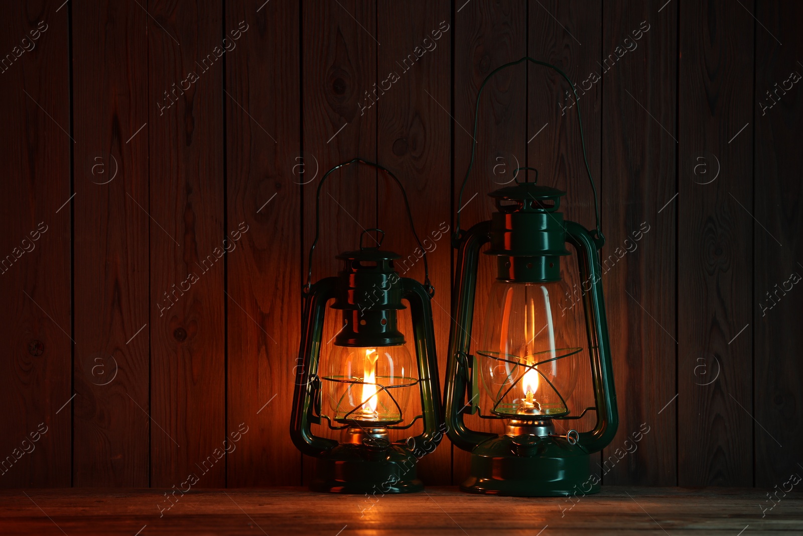 Photo of Two vintage kerosene lanterns on wooden table