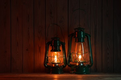 Photo of Two vintage kerosene lanterns on wooden table