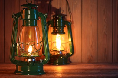 Photo of Vintage kerosene lanterns on wooden table, space for text