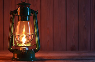 Photo of One vintage kerosene lantern on wooden table, space for text