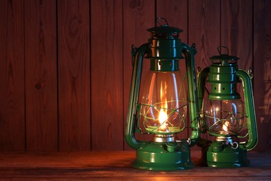 Photo of Vintage kerosene lanterns on wooden table, space for text