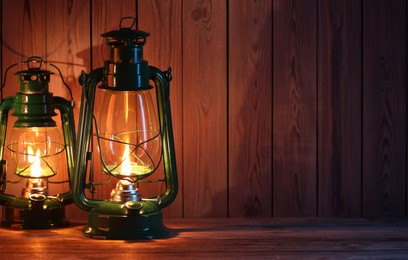 Photo of Vintage kerosene lanterns on wooden table, space for text