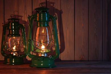 Photo of Vintage kerosene lanterns on wooden table, space for text