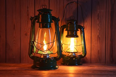 Photo of Two vintage kerosene lanterns on wooden table