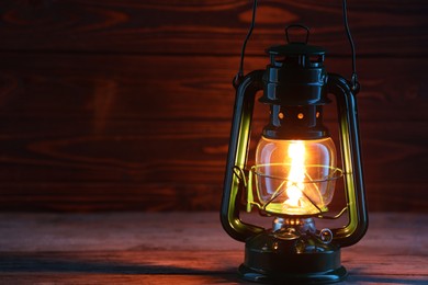 Photo of One vintage kerosene lantern on wooden table, space for text