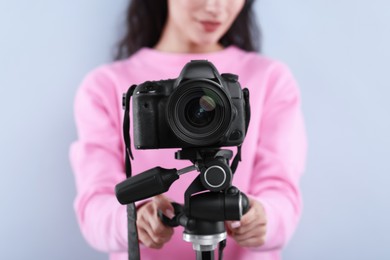 Photo of Woman with professional video camera on light grey background, selective focus