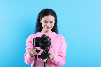 Photo of Woman with professional video camera on light blue background