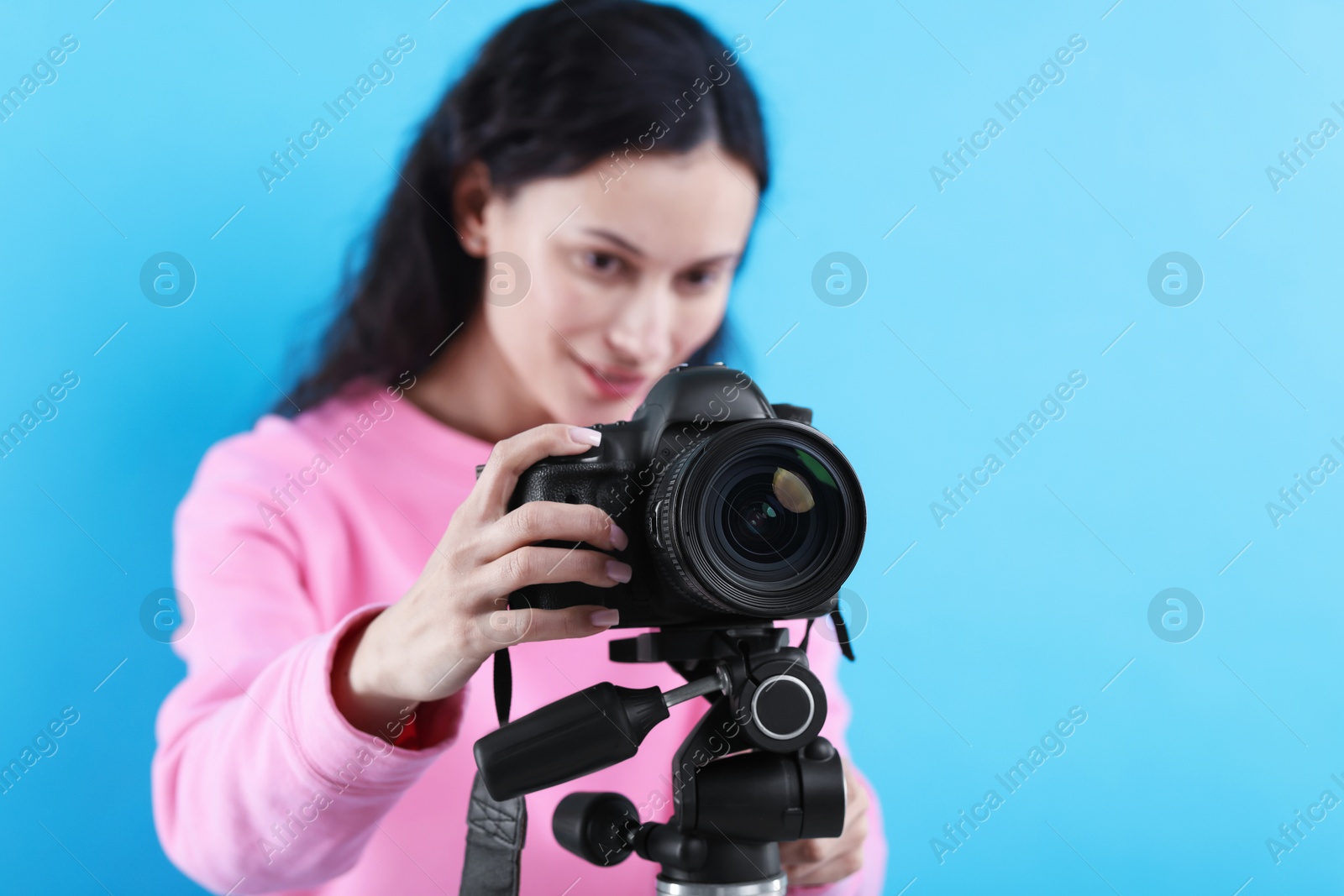 Woman with professional video camera on light blue background, selective focus. Space for text Photo of Woman with professional video camera on light blue background, selective focus. Space for text