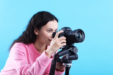 Photo of Woman with professional video camera on light blue background, space for text