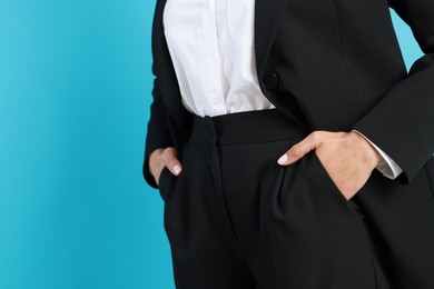 Photo of Confident business woman in suit on light blue background, closeup. Space for text