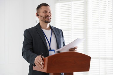 Photo of Man giving public speech with microphone at lectern indoors