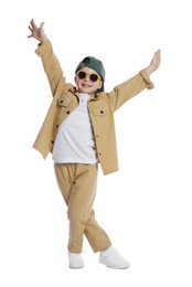 Photo of Happy little boy in sunglasses and baseball hat dancing on white background
