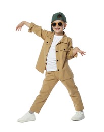 Photo of Happy little boy in sunglasses and baseball hat dancing on white background