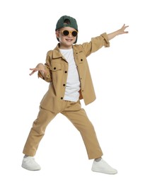 Photo of Happy little boy in sunglasses and baseball hat dancing on white background
