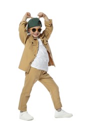 Photo of Happy little boy in sunglasses and baseball hat dancing on white background