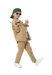 Photo of Happy little boy in stylish clothes dancing and showing thumbs up on white background
