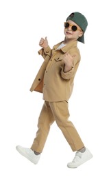 Photo of Happy little boy in stylish clothes dancing and showing thumbs up on white background