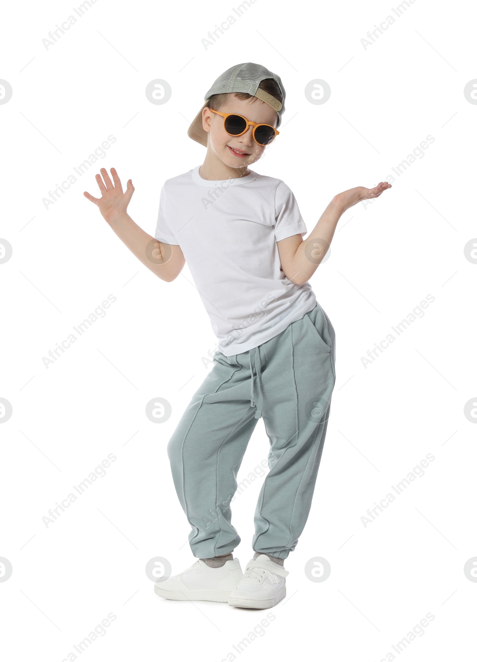 Photo of Happy little boy in sunglasses and baseball hat dancing on white background