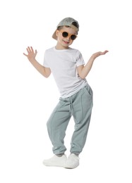 Photo of Happy little boy in sunglasses and baseball hat dancing on white background